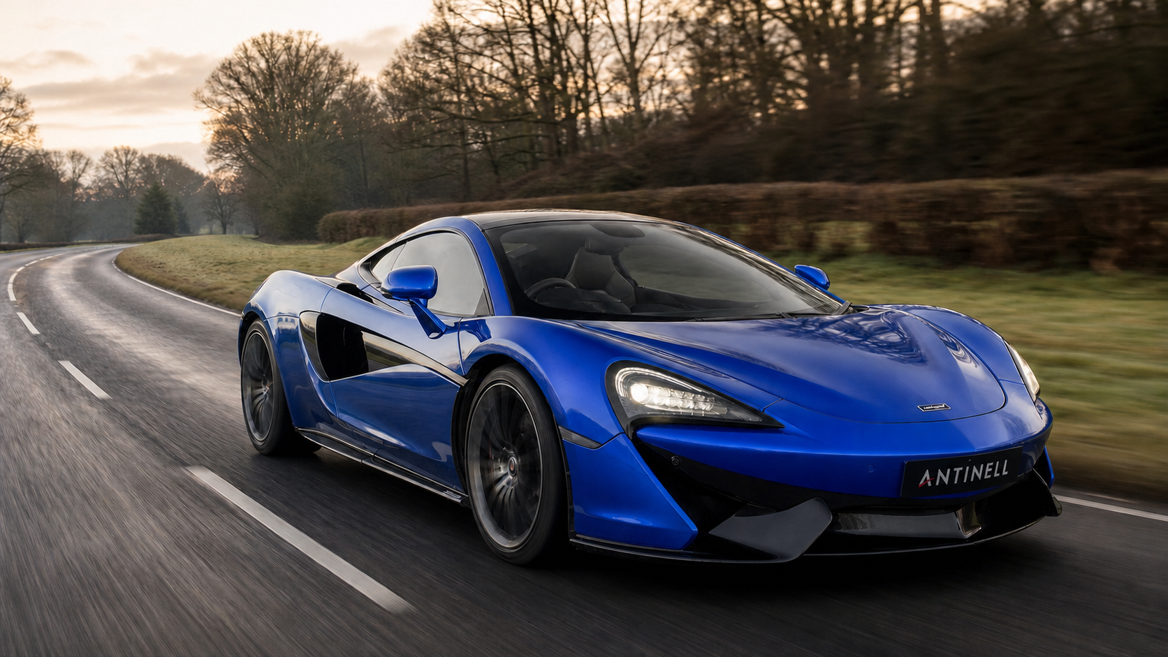 Blue McLaren 570GT driving on a Surrey country road